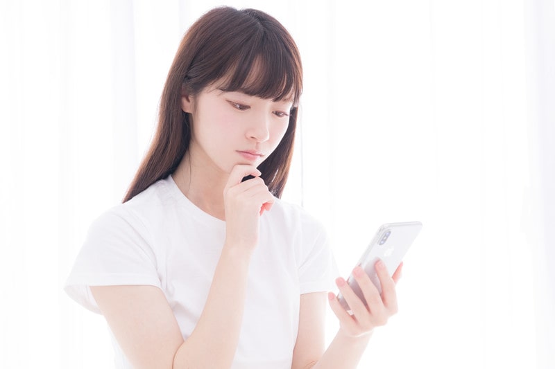 スマホを見て悩む女性